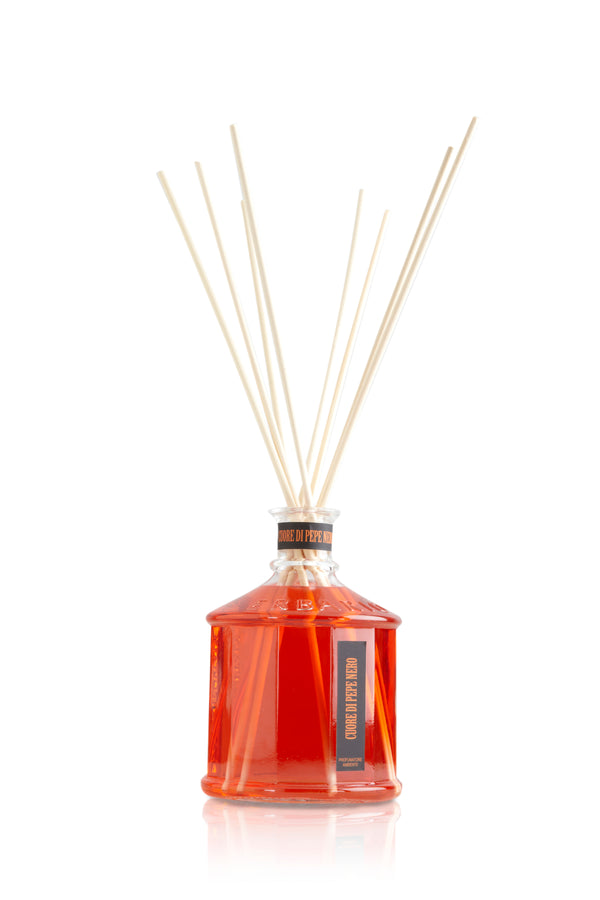 Glass bottle with red color heart of black pepper home fragrance liquid and reed sticks.
