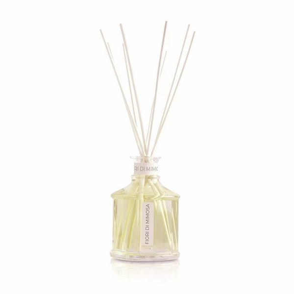 Glass bottle with yellow color Mimosa flowers home fragrance liquid and reed sticks.