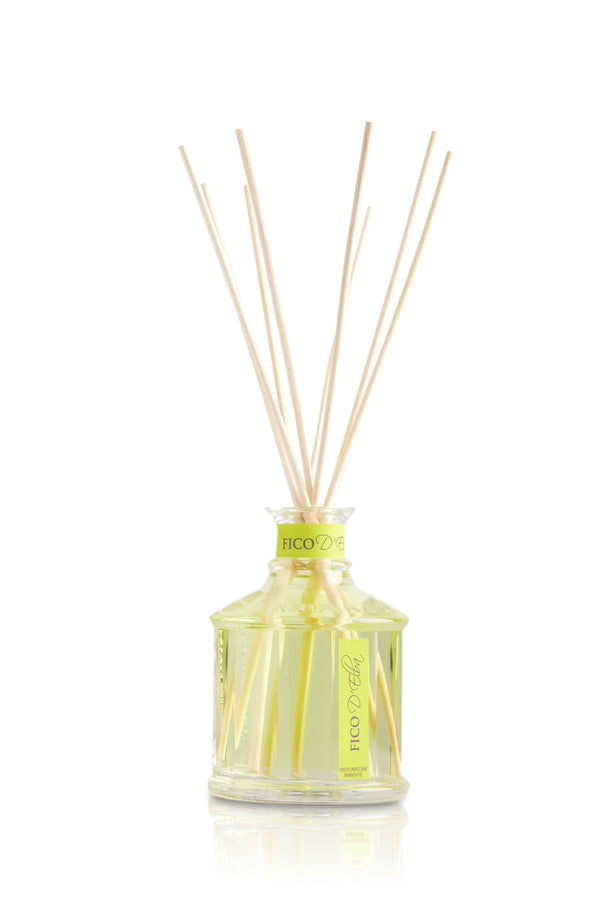 Glass bottle with light green color figs of Elba home fragrance liquid and reed sticks.