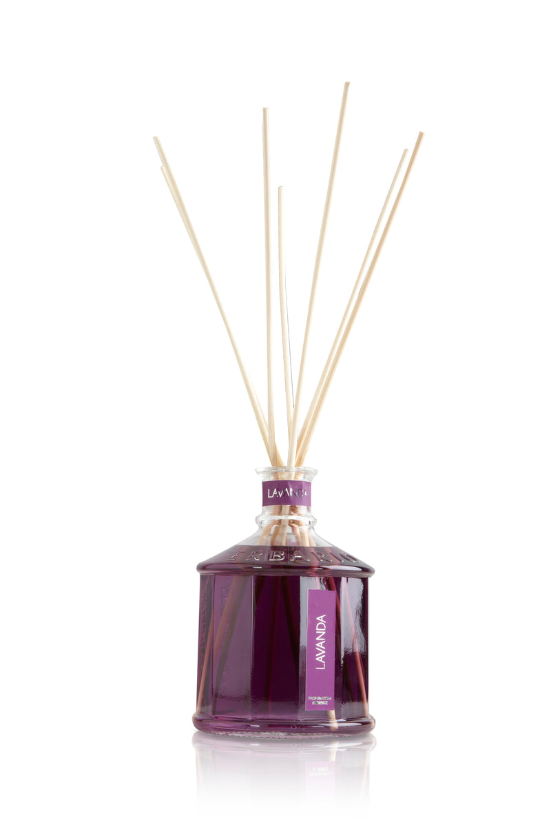 Glass bottle with purple color lavender home fragrance liquid and reed sticks.